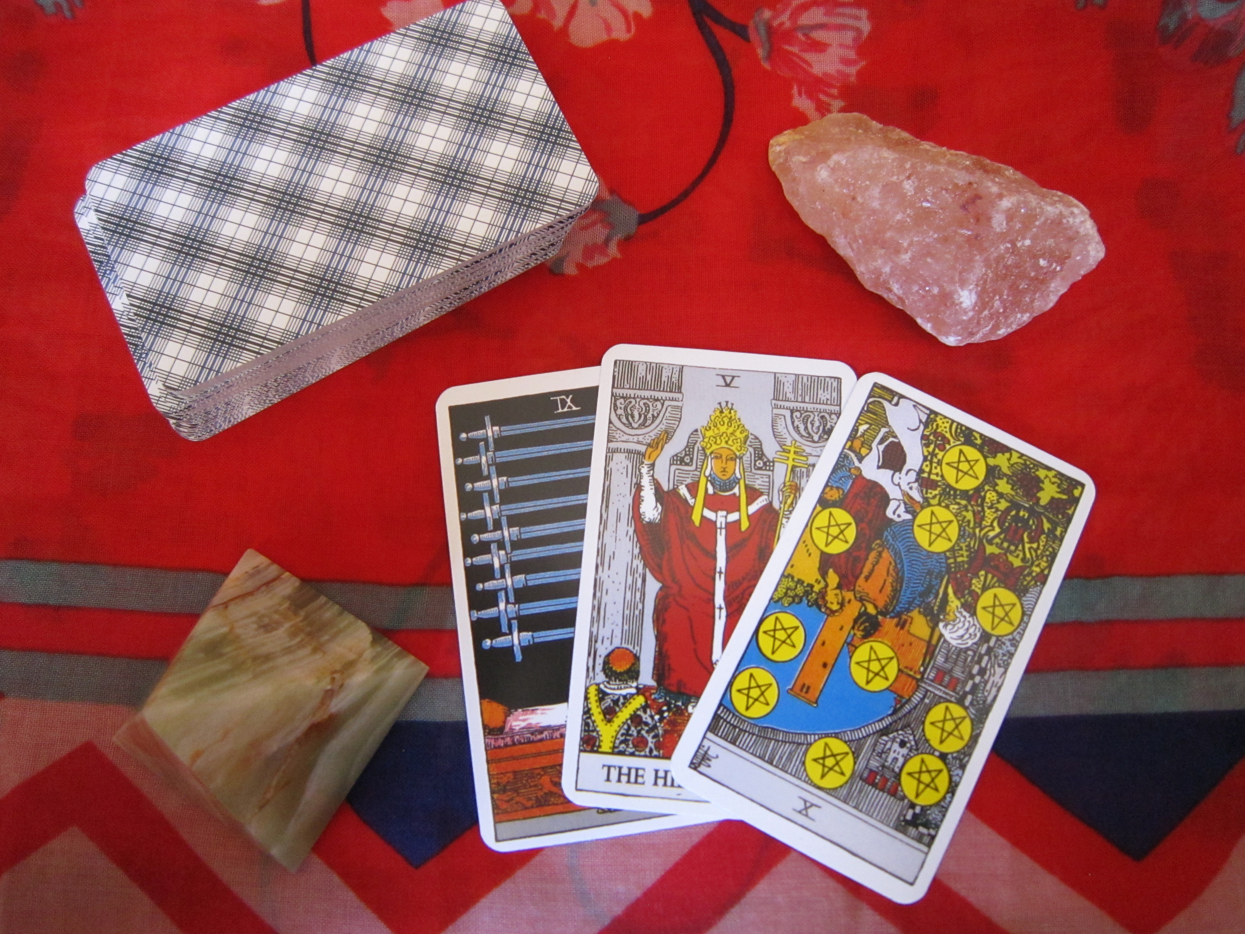 Tarot card reading with 3 cards which show the 9 of swords, the heirophant, and the ten of pentacles.